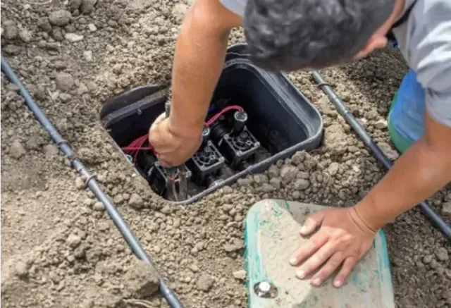 Person working on irrigation valves.